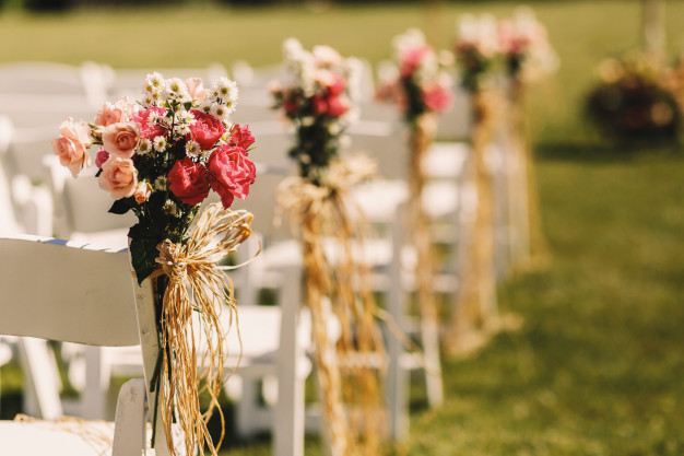 Cómo elegir las flores para tu boda - Ramos rosas en sillas blancas
